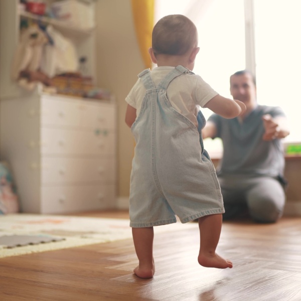 A toddler walking towards a parent.