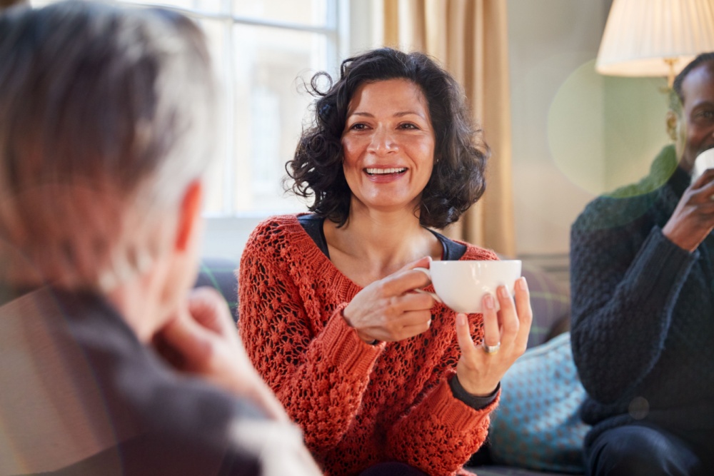 A woman talking to a man while drinking tea.