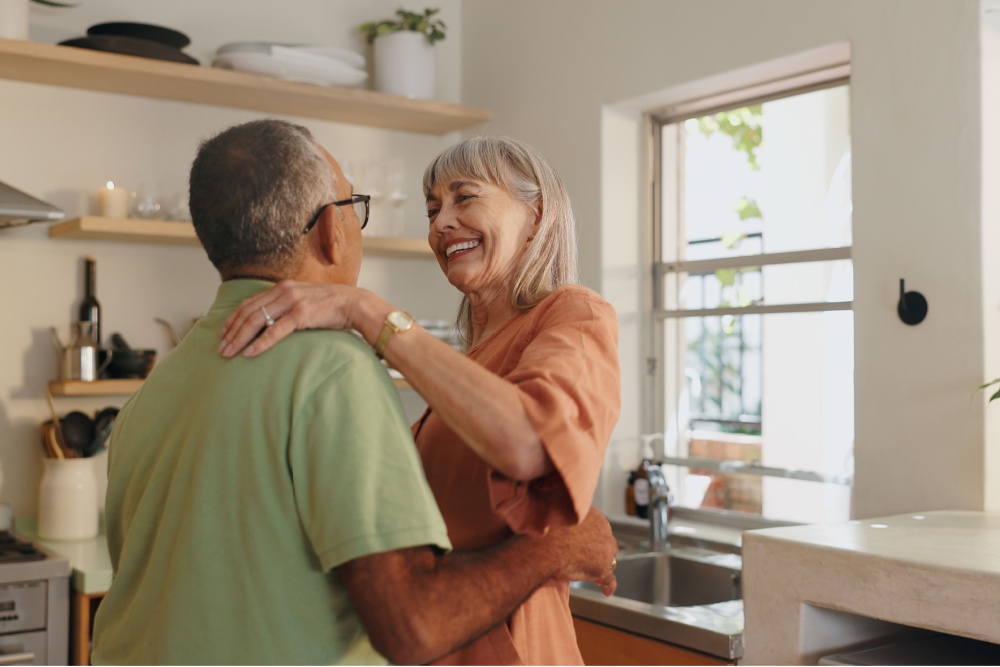 An older couple dancing together at home.