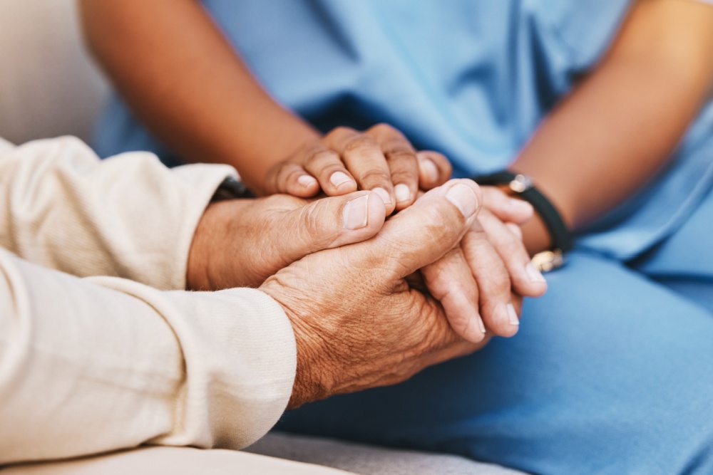 An elderly person holding hands with a nurse.